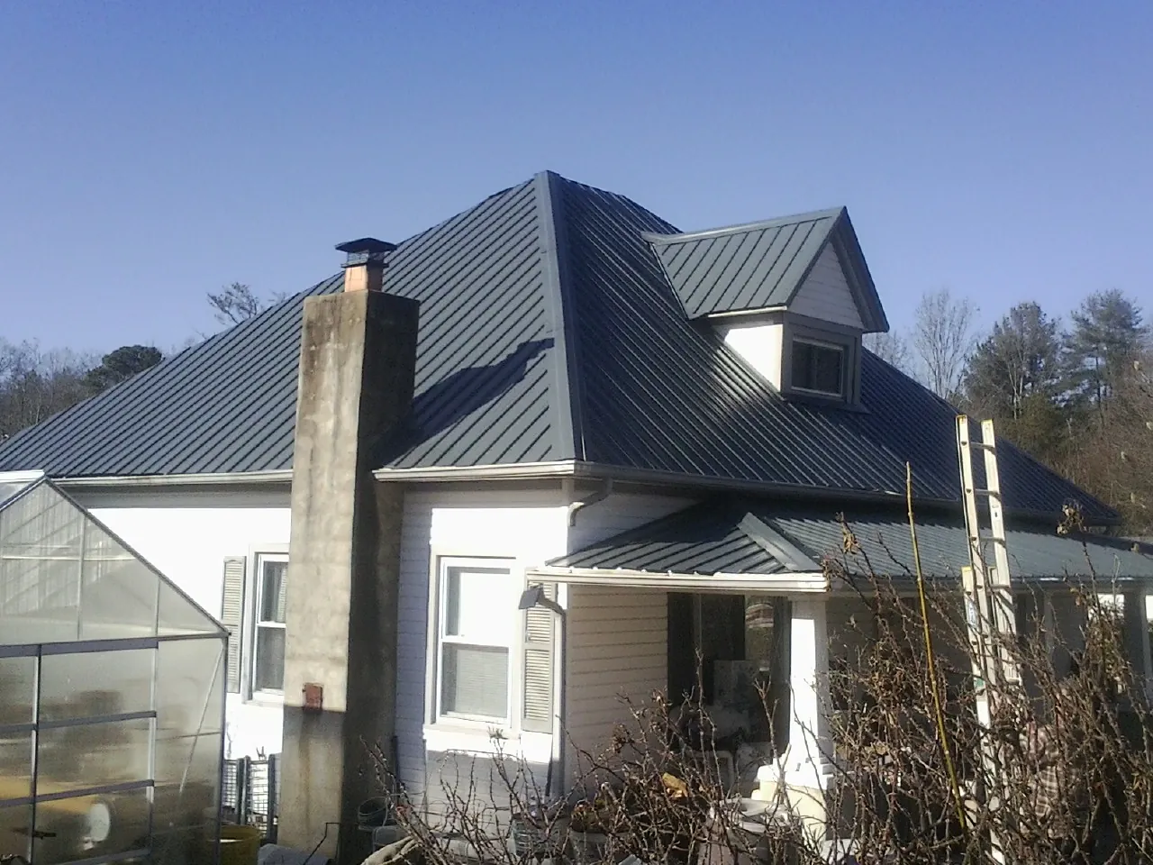 Dark blue standing seam metal roof on a white farmhouse with dormer — Slate & Tile Roof Repair by Roofing Brothers in Peebles