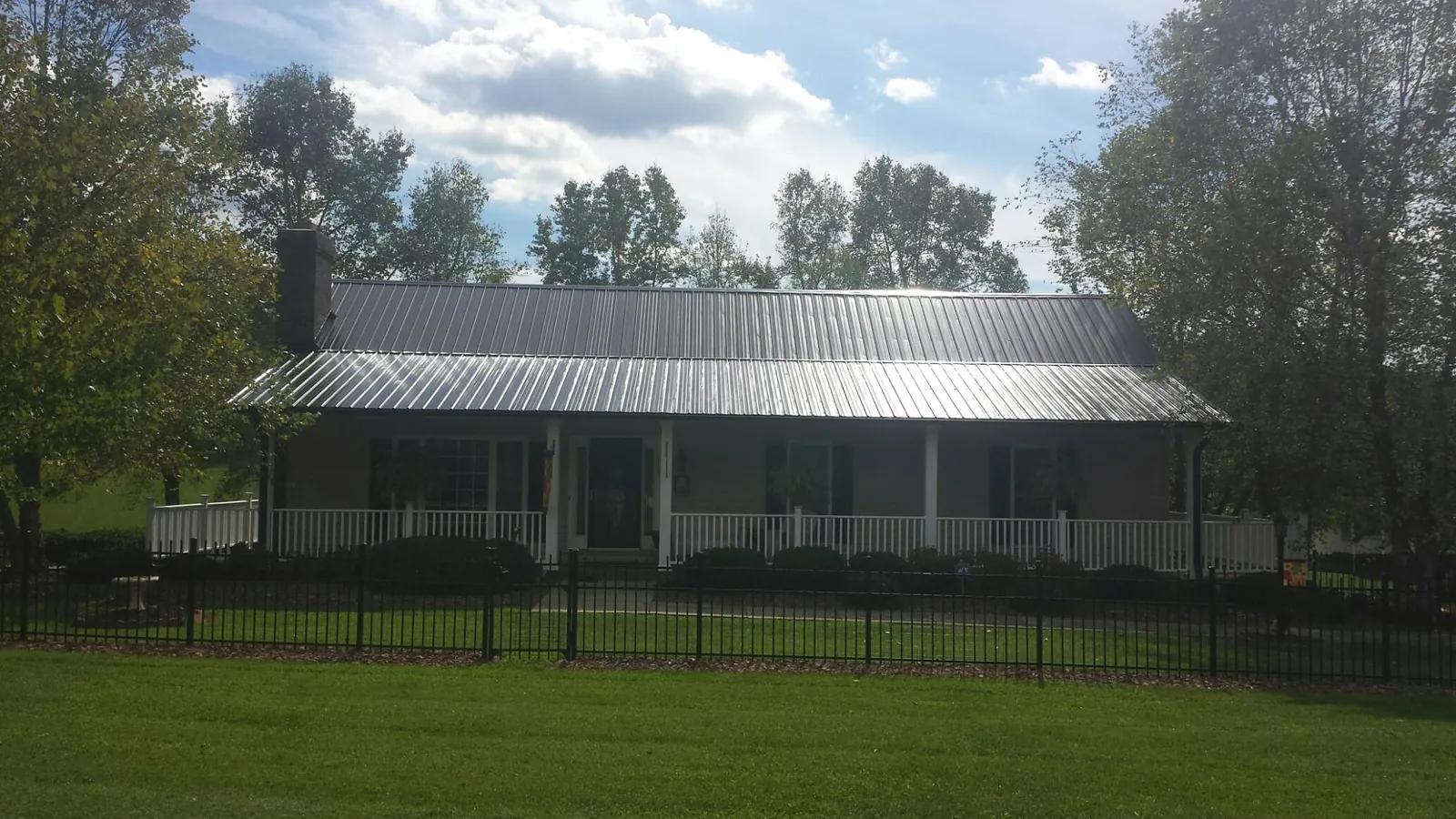 Gray metal roof on a brick ranch with a full width front porch — Gutter Guard Installation work by our crew in Peebles