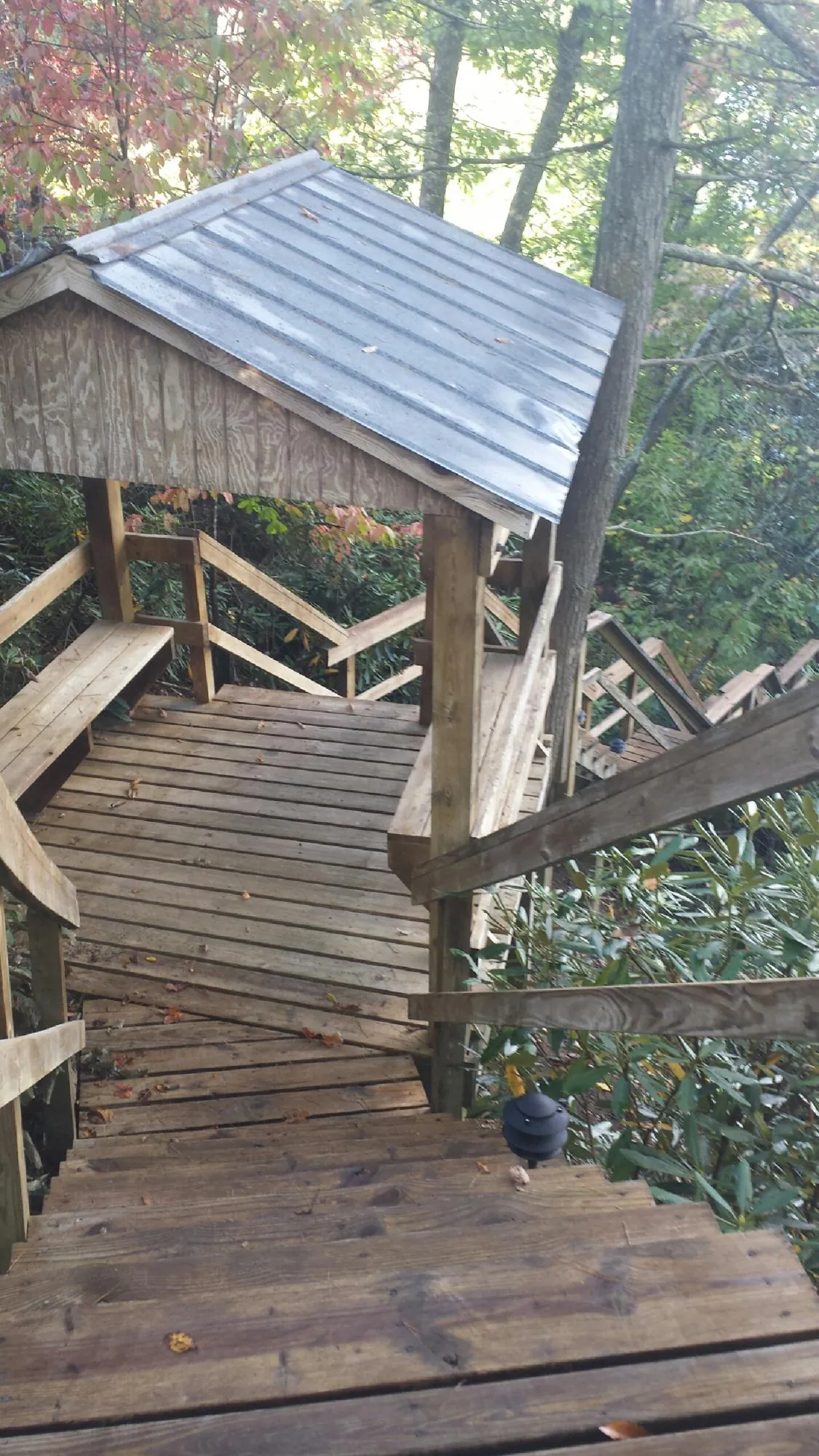 Metal roofed shelter over wooden steps on a wooded walkway — Skylight Repair & Installation work by our crew in Peebles
