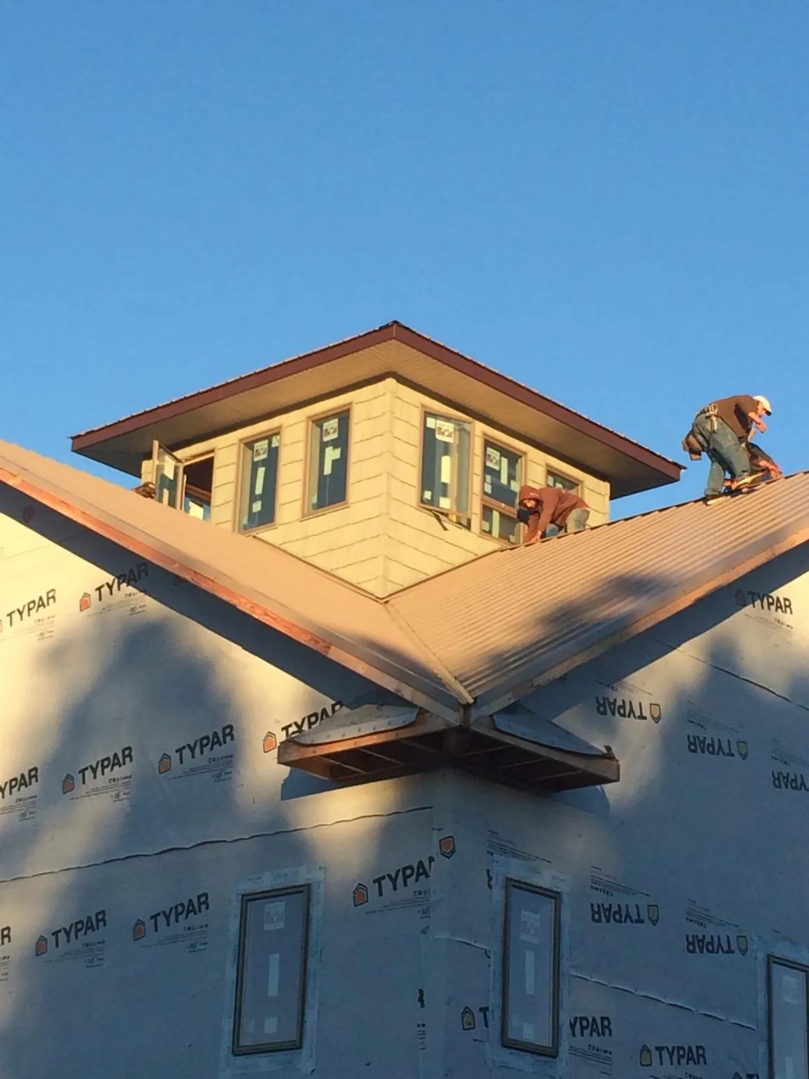 Roofers working around a rooftop cupola on a new metal roof at sunset — Roof Waterproofing in Peebles by Roofing Brothers